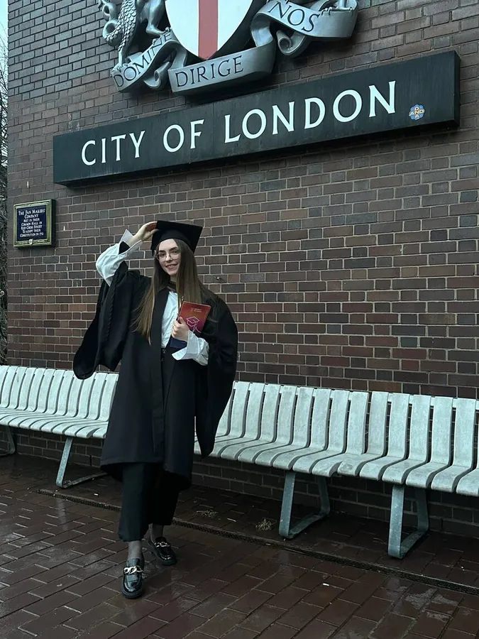Соня в мантии выпускницы у здания City of London